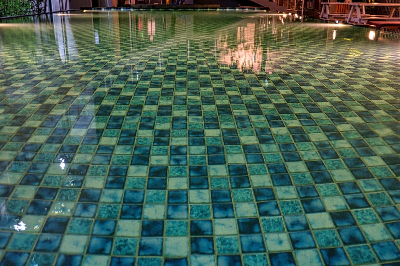 Close-up of teal glazed pool tile under clear rippling water